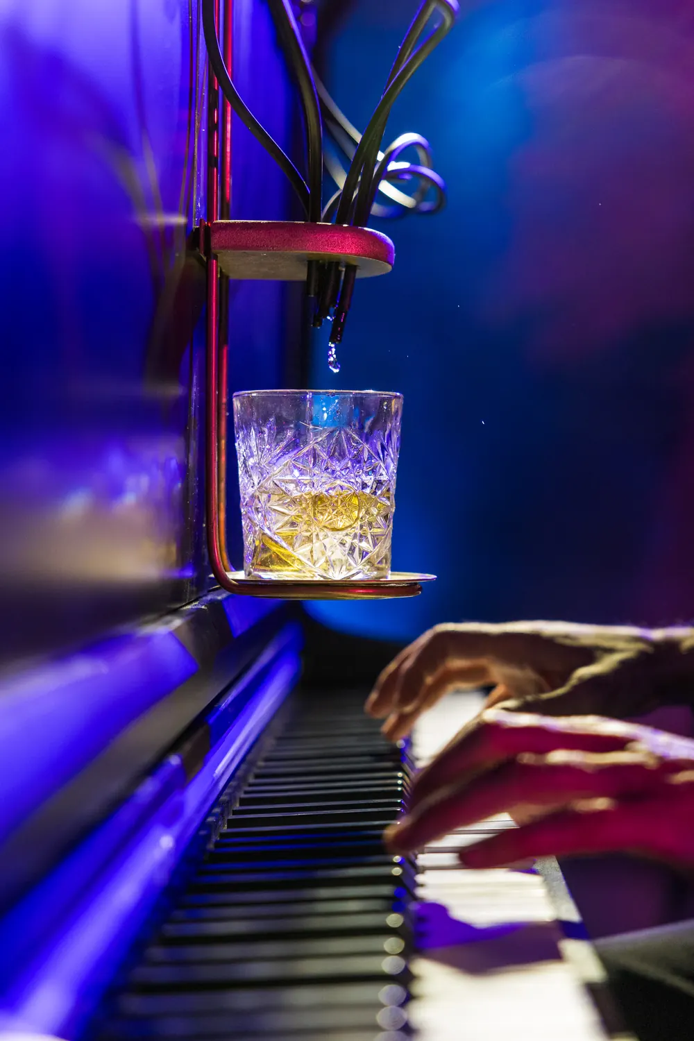 Cocktail versé goutte à goutte par le Pianocktail sous lumière bleue