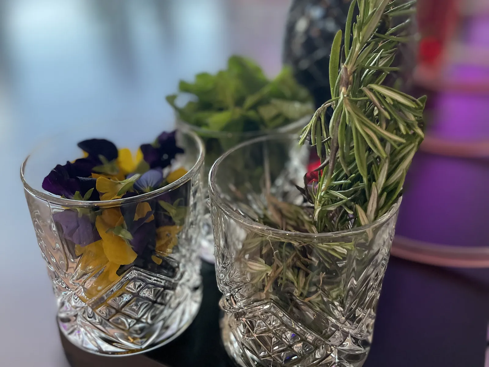 Fleurs comestibles, menthe et romarin dans des verres en cristal