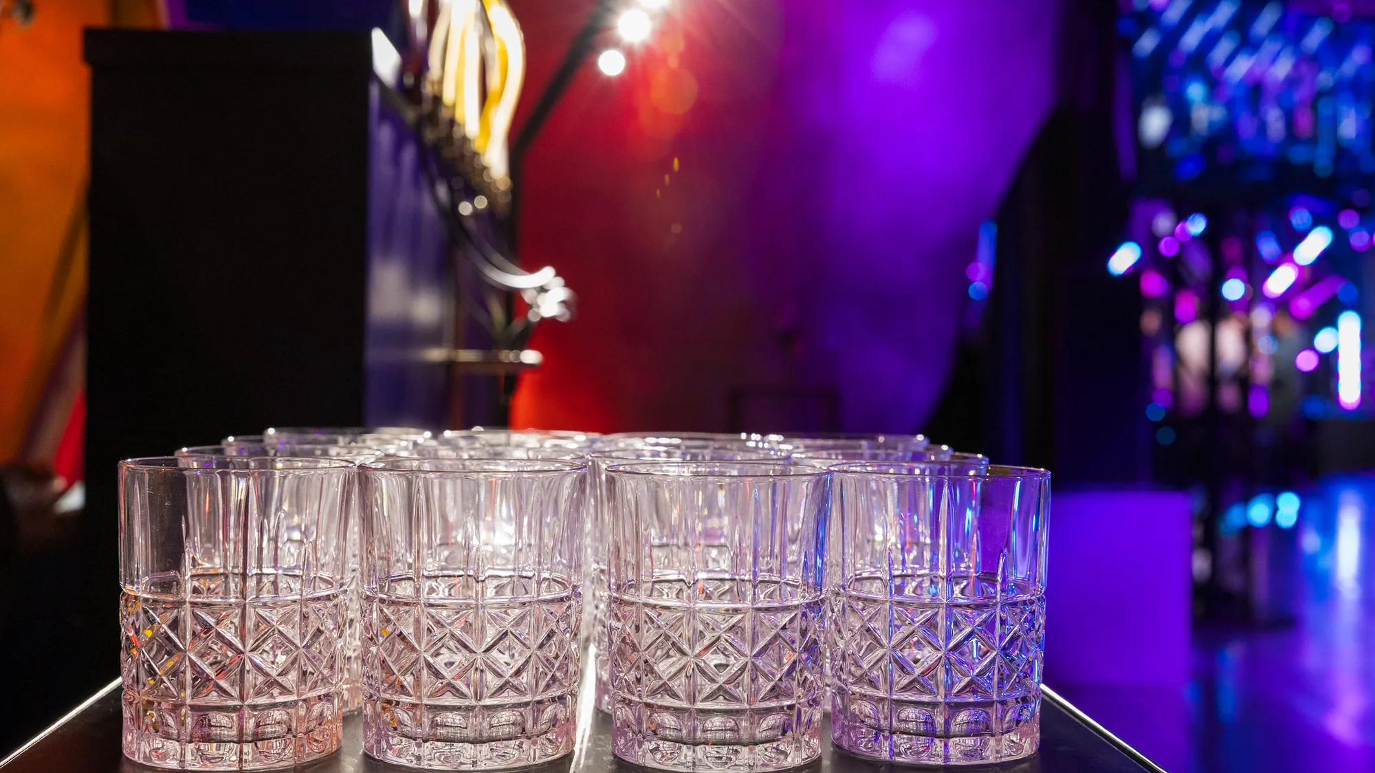 Verres en cristal alignés au pied du Pianocktail, sous les lumières d'une soirée