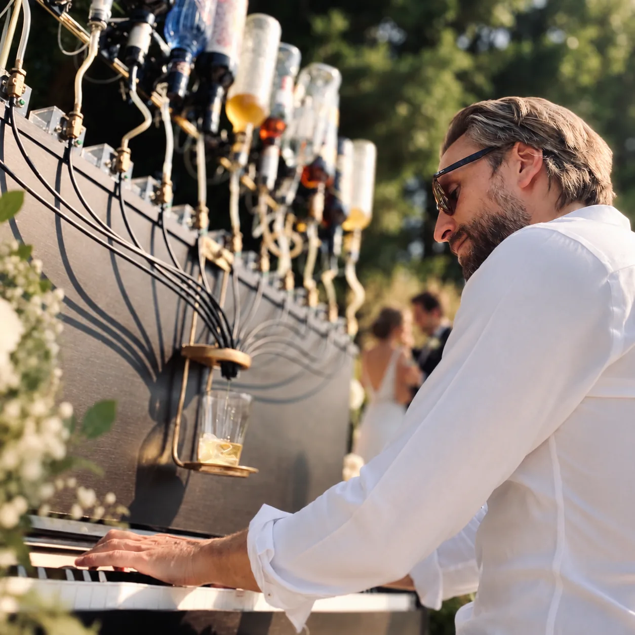 Le pianiste joue le Pianocktail en plein air pendant que les mariés trinquent en arrière-plan