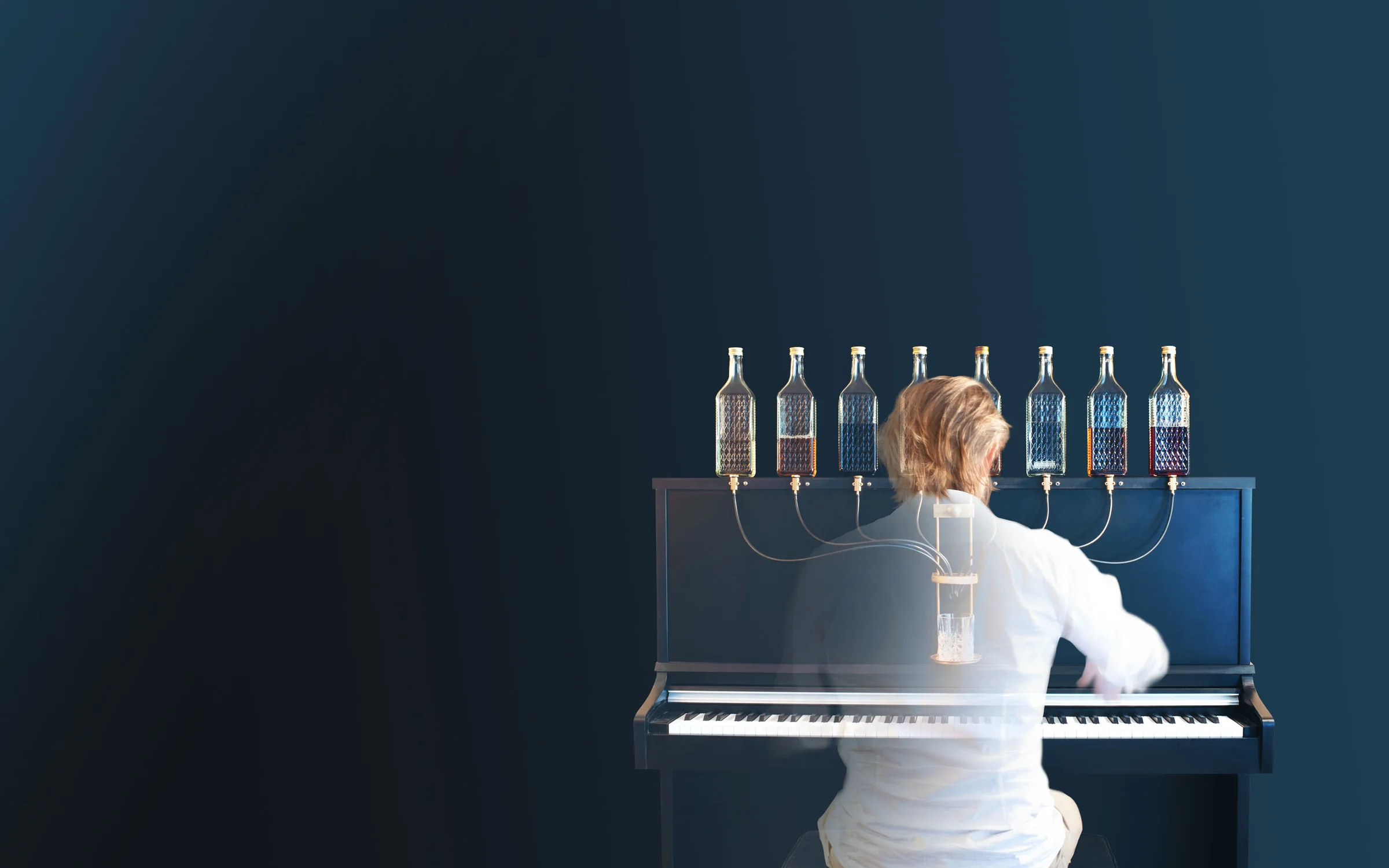 Pianiste jouant le Pianocktail, huit bouteilles reliées à un verre