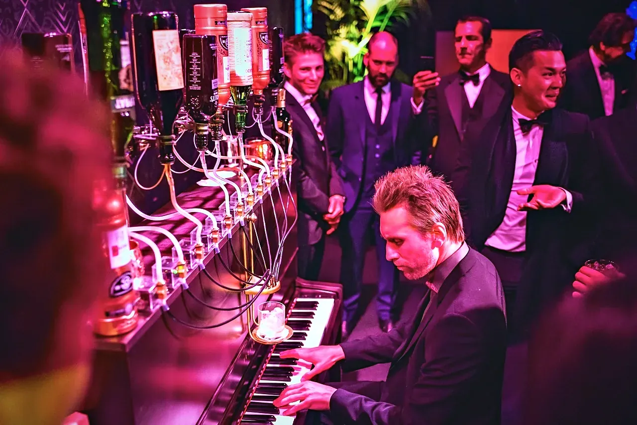 Invités en smoking autour du pianiste lors d'une soirée Nolet's